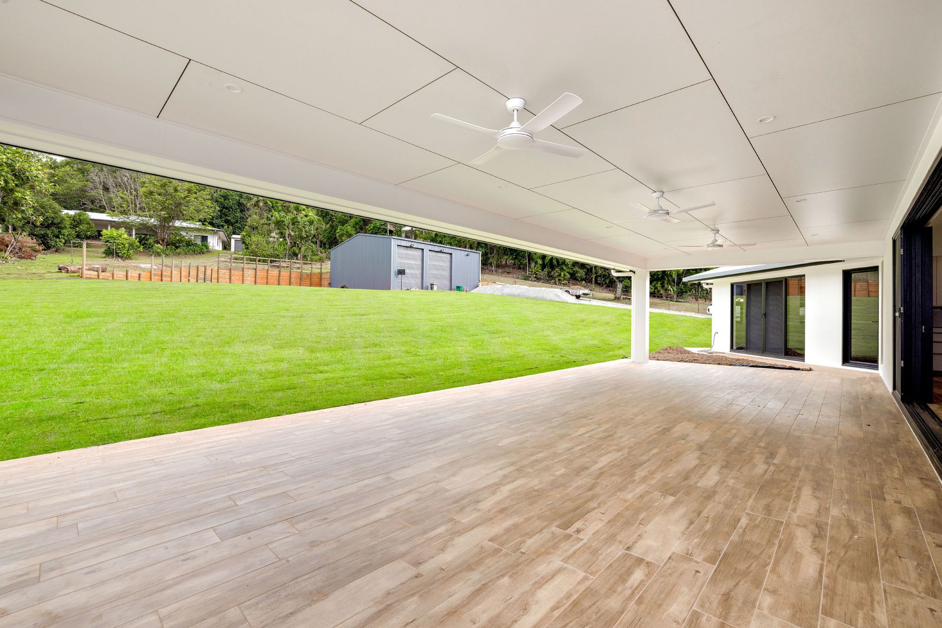 A Spacious, Covered Outdoor Patio With Light Wood-look Tiled Floors — Ashlee Jones Homes in Gordonvale, QLD