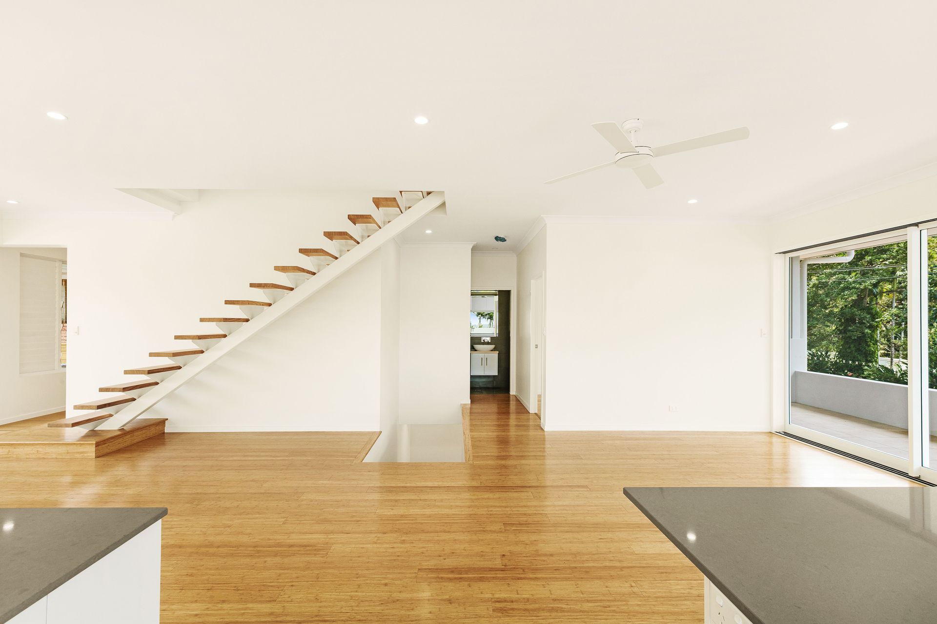 A Modern, Open-plan Living Space With Light Wood Flooring — Ashlee Jones Homes in Gordonvale, QLD