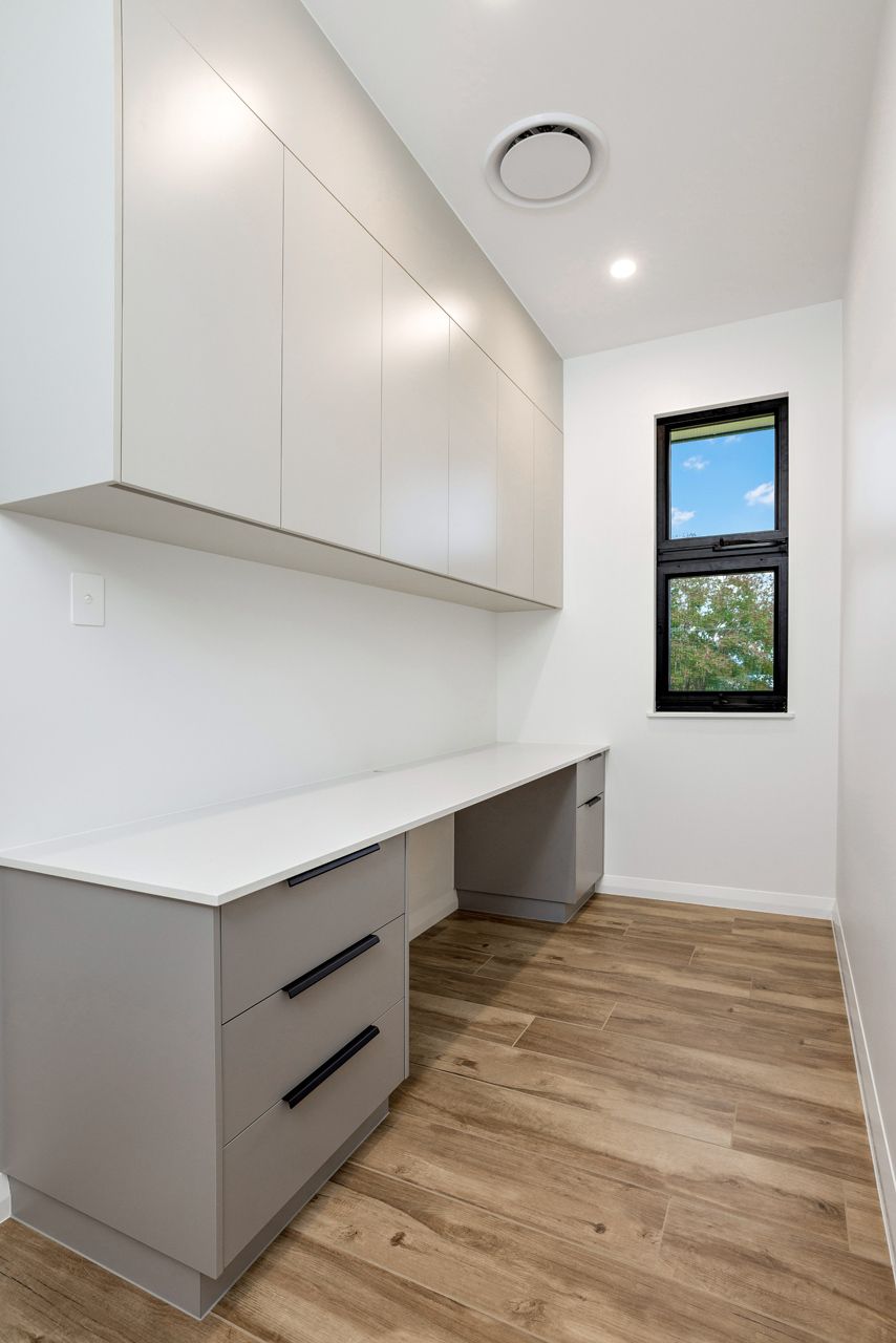 A Home Office With Light Grey Cabinets Above a White Desk — Ashlee Jones Homes in Gordonvale, QLD