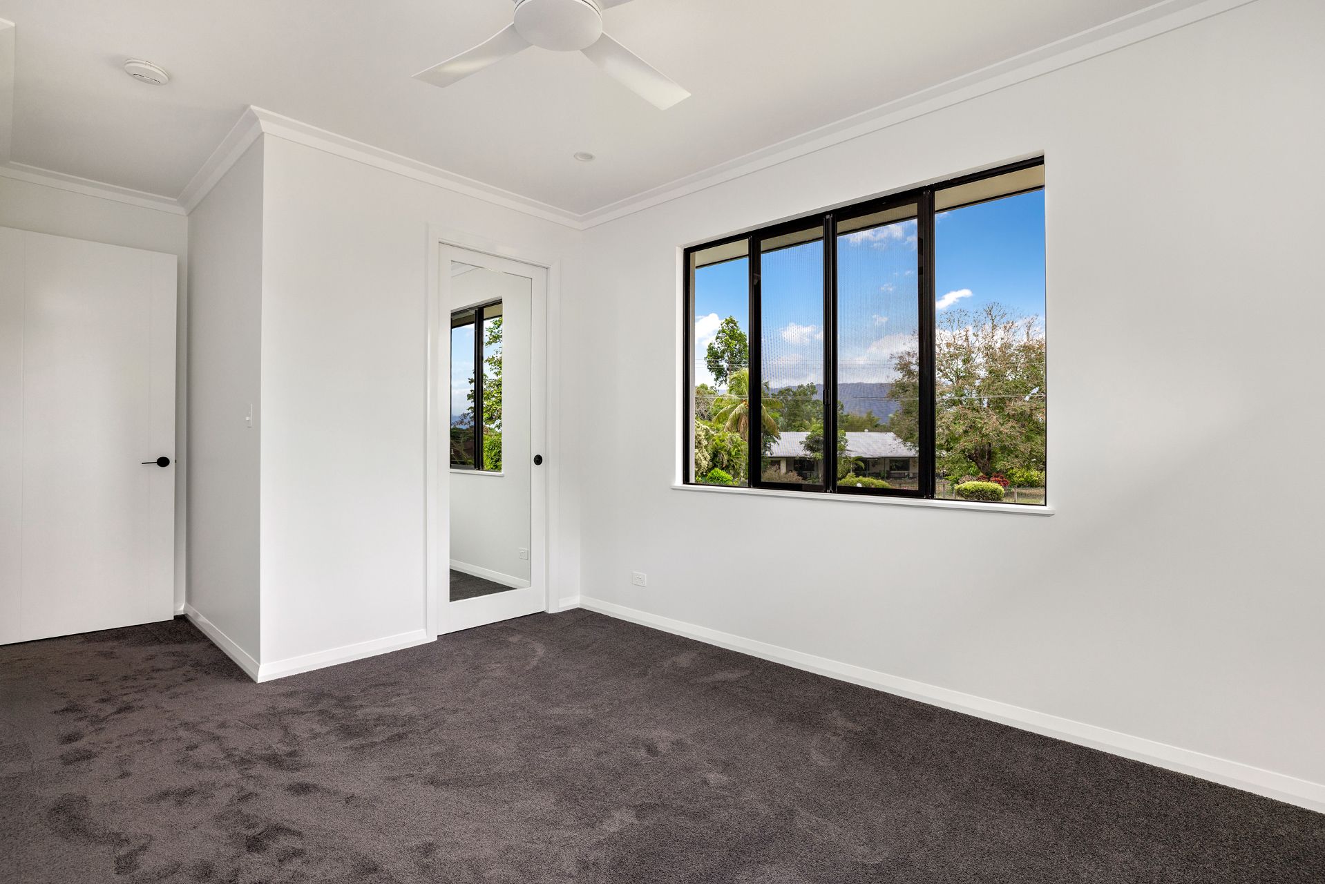An Empty Bedroom With White Walls, Dark Gray Carpet — Ashlee Jones Homes in Gordonvale, QLD