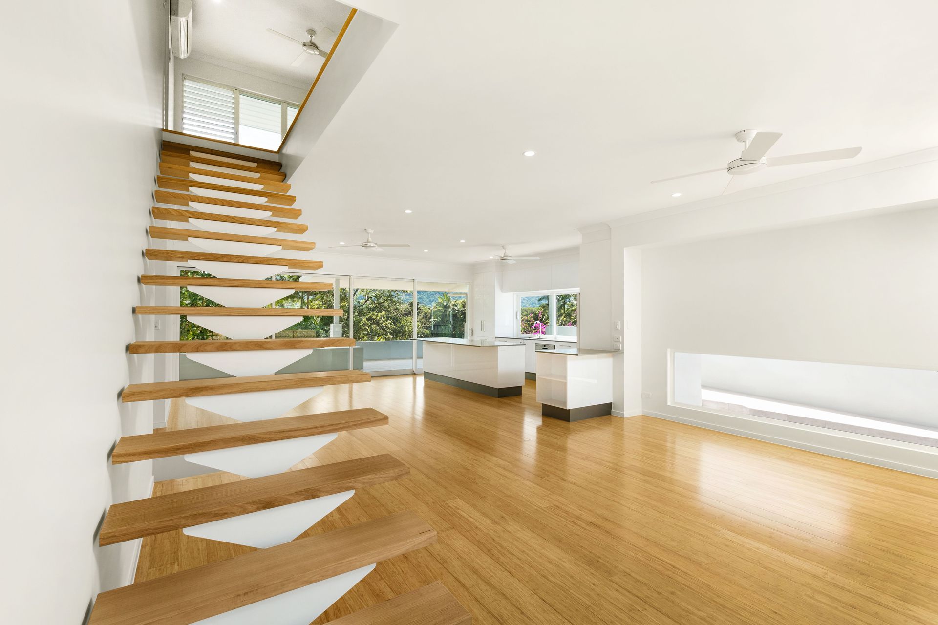 An Open-concept Room Features a Floating Wooden Staircase — Ashlee Jones Homes in Gordonvale, QLD