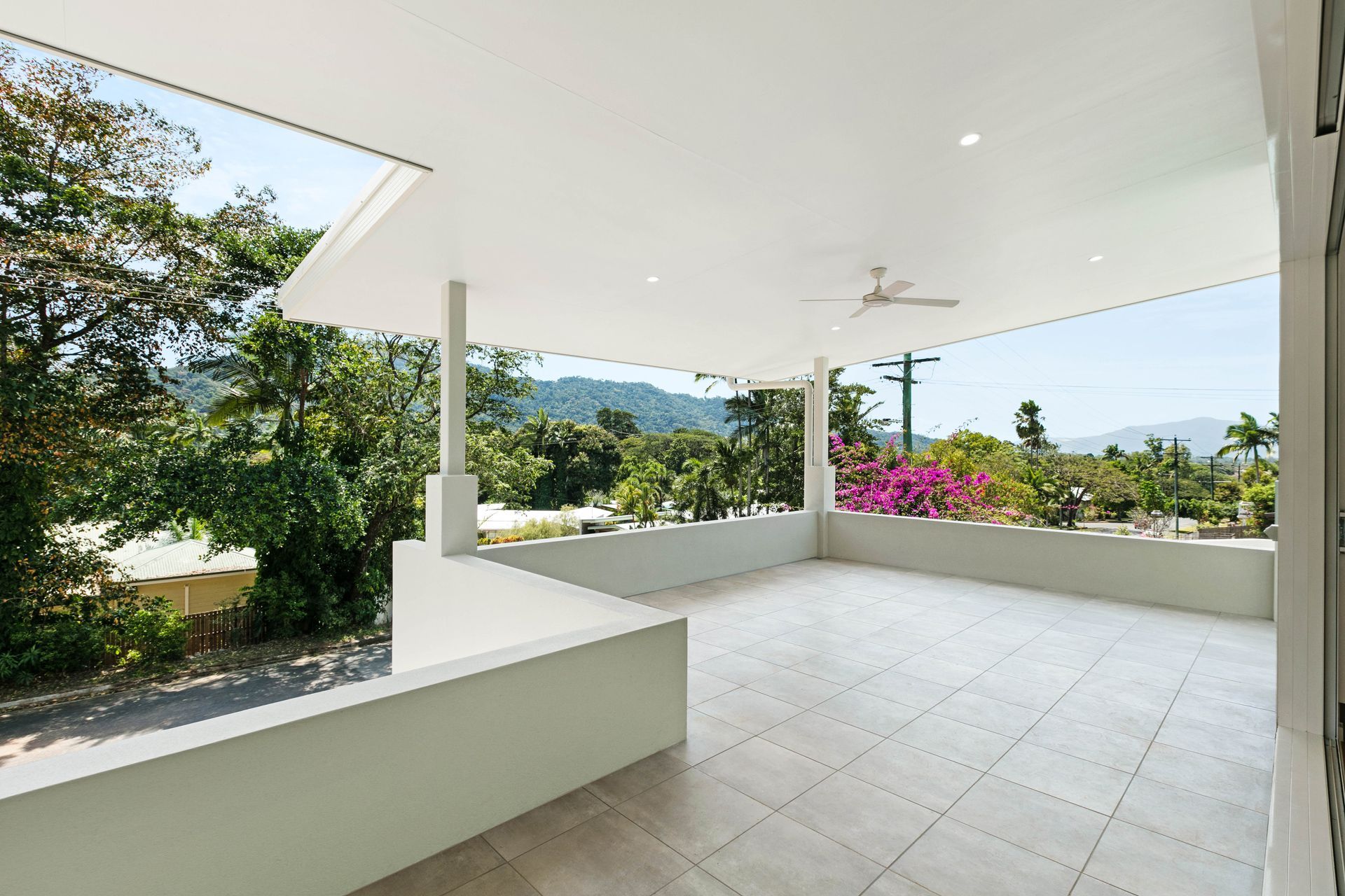 A Spacious, Covered Outdoor Balcony With Light-colored Tile Flooring — Ashlee Jones Homes in Gordonvale, QLD