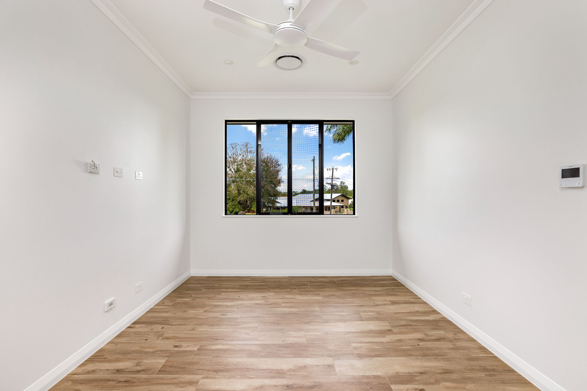 A Bright, Empty Room With White Walls, Wood-look Flooring — Ashlee Jones Homes in Gordonvale, QLD
