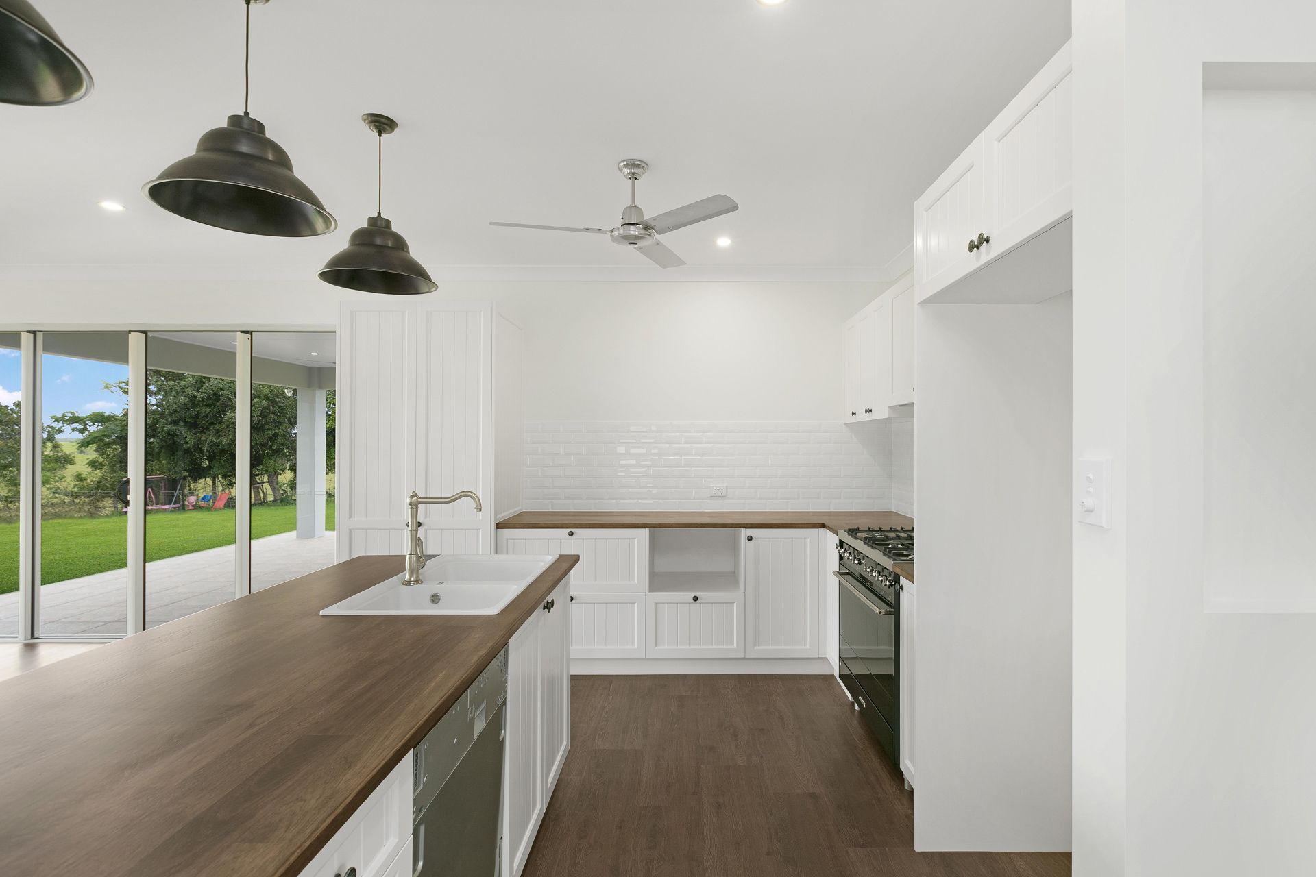 A Bright Modern Kitchen With a Wooden Island Bench — Ashlee Jones Homes in Gordonvale, QLD