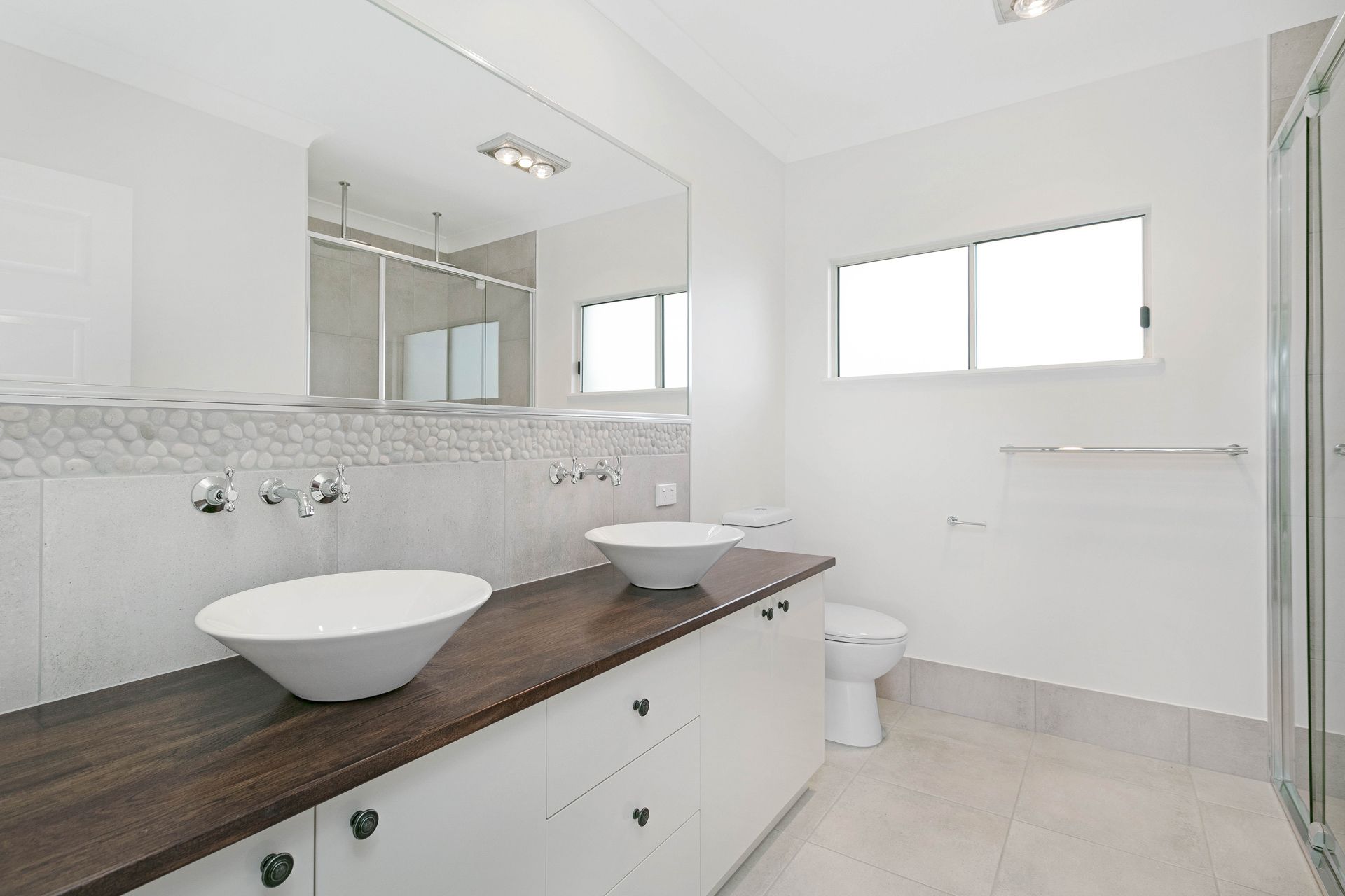 A Bright Bathroom With a Dual White Vessel Sink Vanity — Ashlee Jones Homes in Gordonvale, QLD