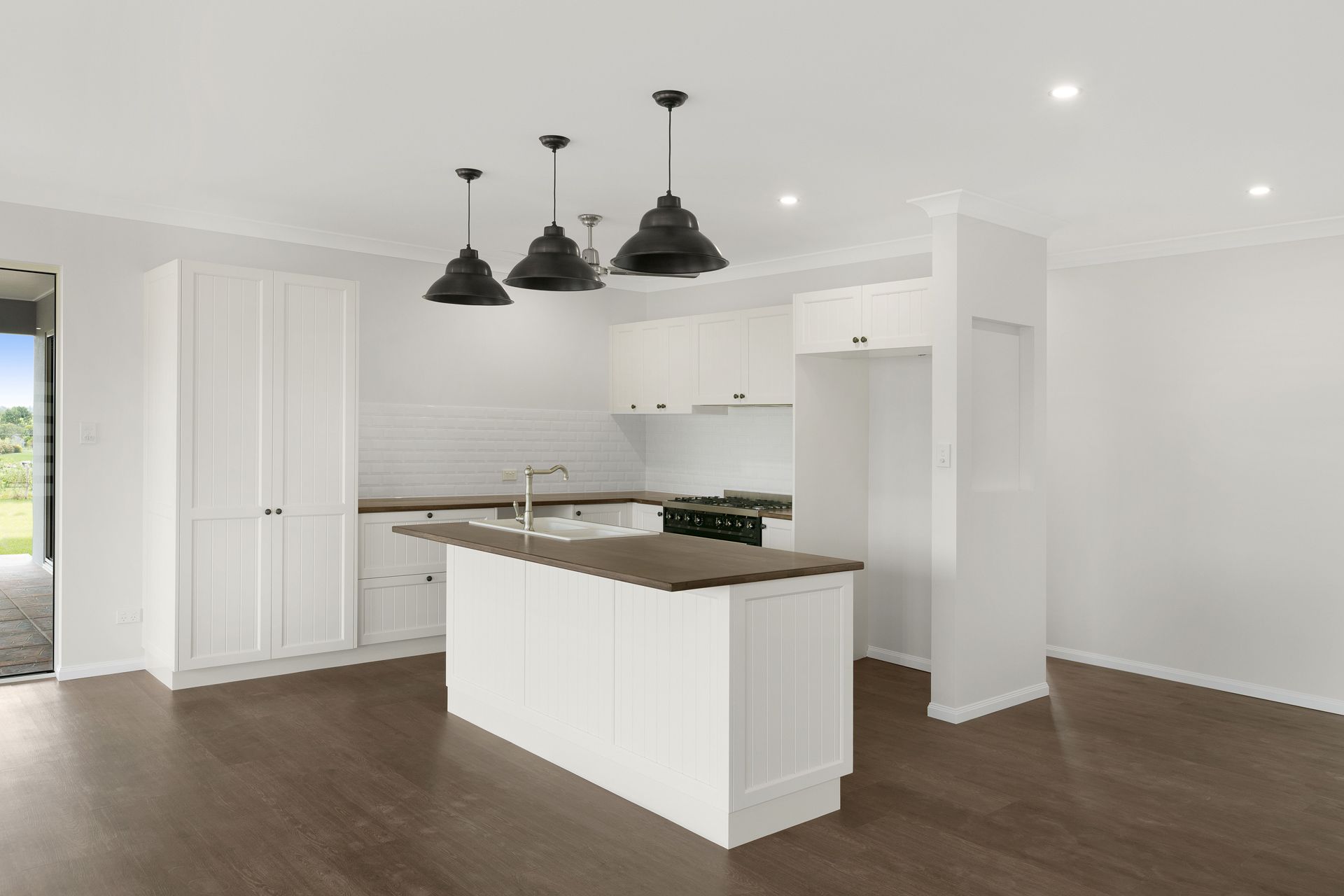 A Modern Kitchen With White Cabinetry, a Dark Countertop Island — Ashlee Jones Homes in Gordonvale, QLD