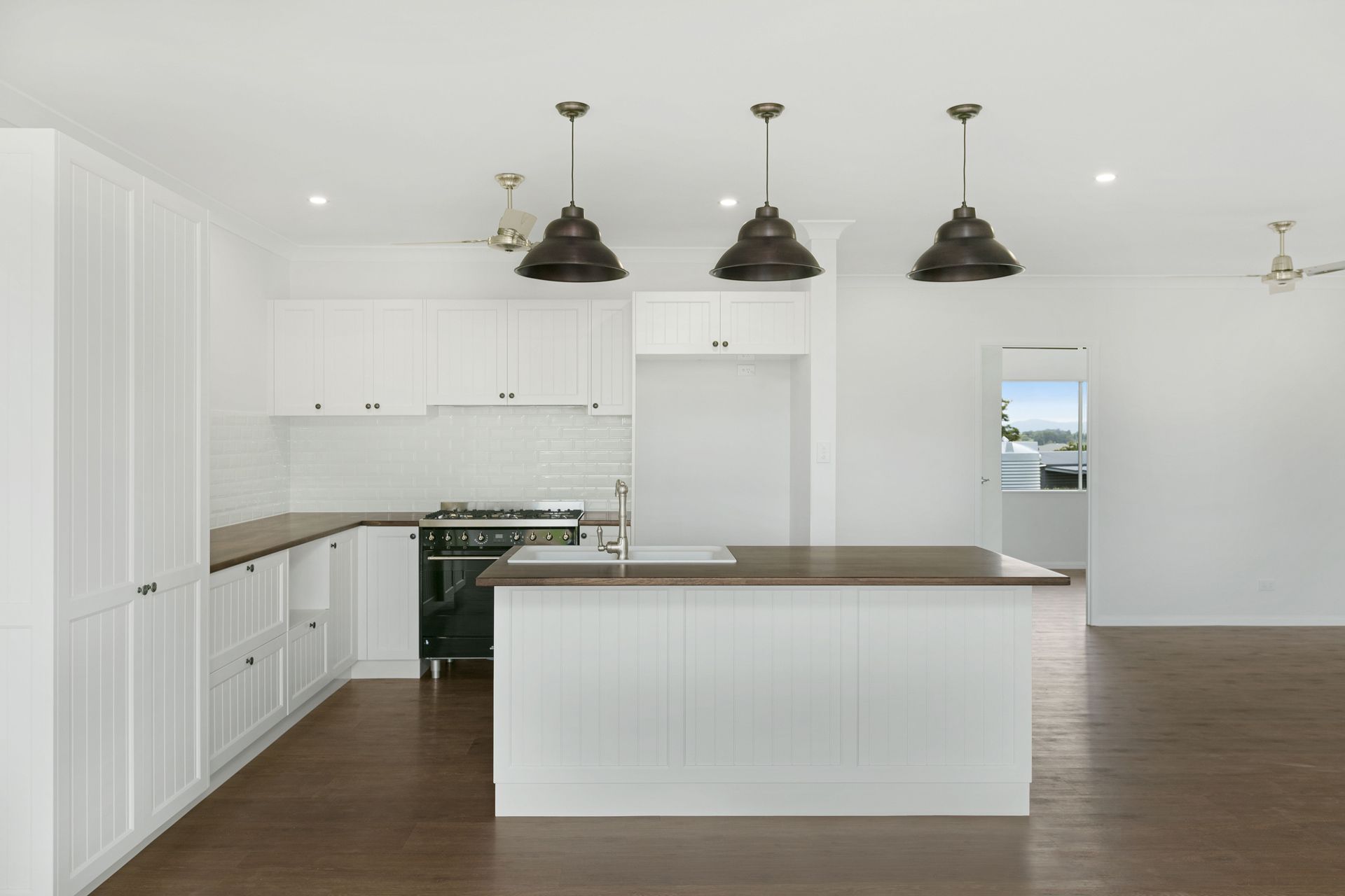 A Modern Kitchen With White Cabinetry, Dark Wood Countertops — Ashlee Jones Homes in Gordonvale, QLD