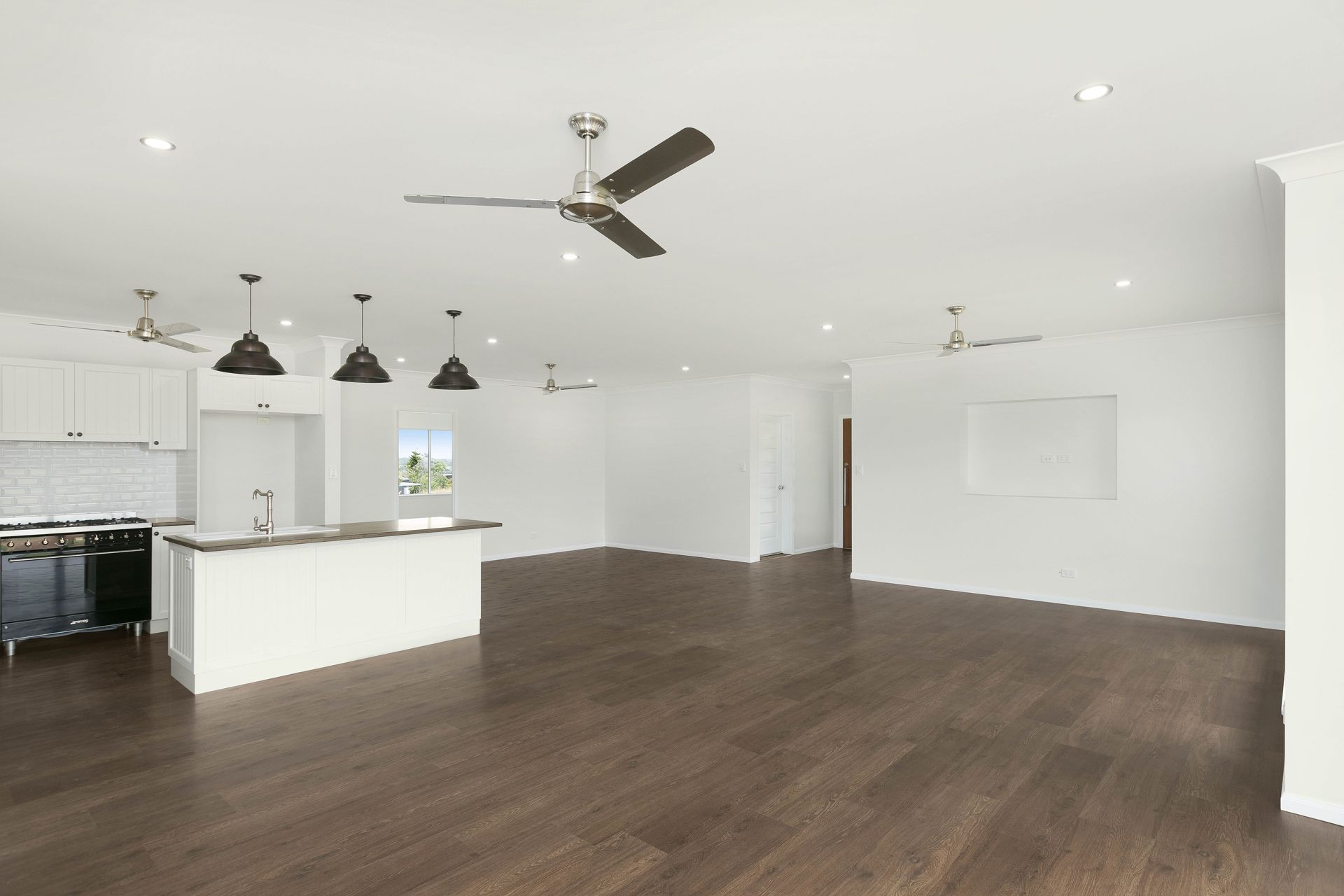 An Open-plan Kitchen and Living Area With a White Island — Ashlee Jones Homes in Gordonvale, QLD