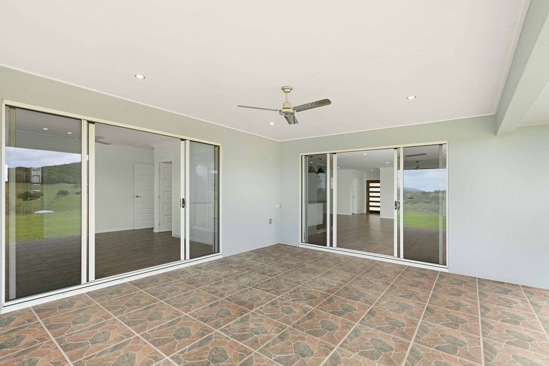 A Modern, Covered Outdoor Patio Featuring Brown Tiled Flooring — Ashlee Jones Homes in Gordonvale, QLD