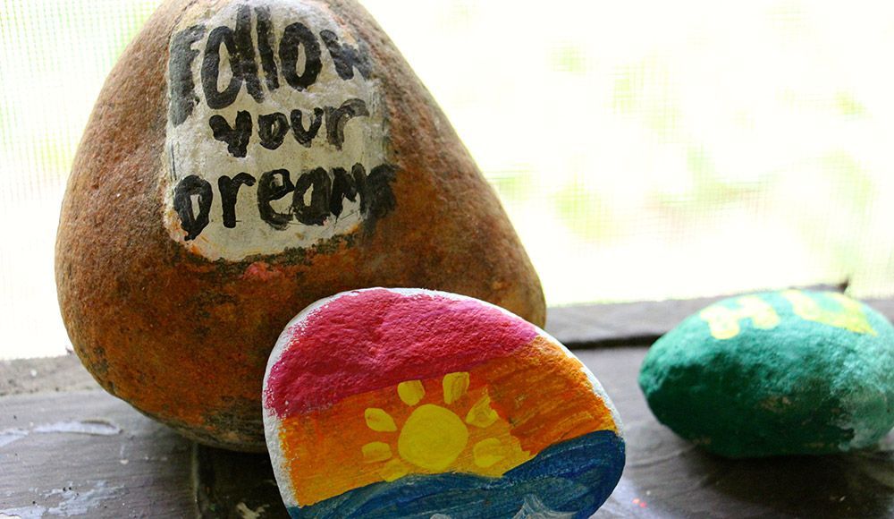 Three painted decorative rocks, one with
