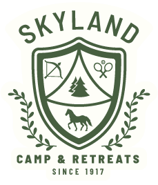 Green shield logo for Skyland Camp & Retreats, featuring icons for archery, tennis, and horses, established in 1917.
