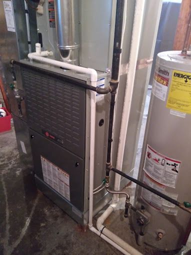 A water heater is sitting next to a furnace in a basement.