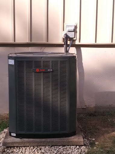 A large air conditioner is sitting outside of a building.