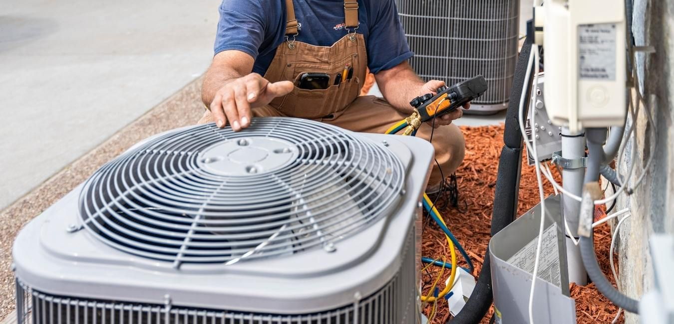 A man is working on an air conditioner outside of a house.
