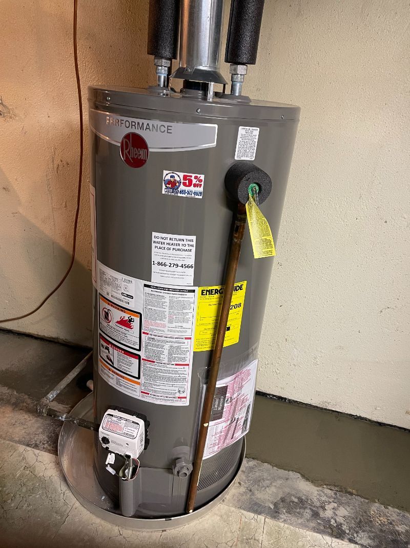 A water heater is sitting on the floor next to a wall.