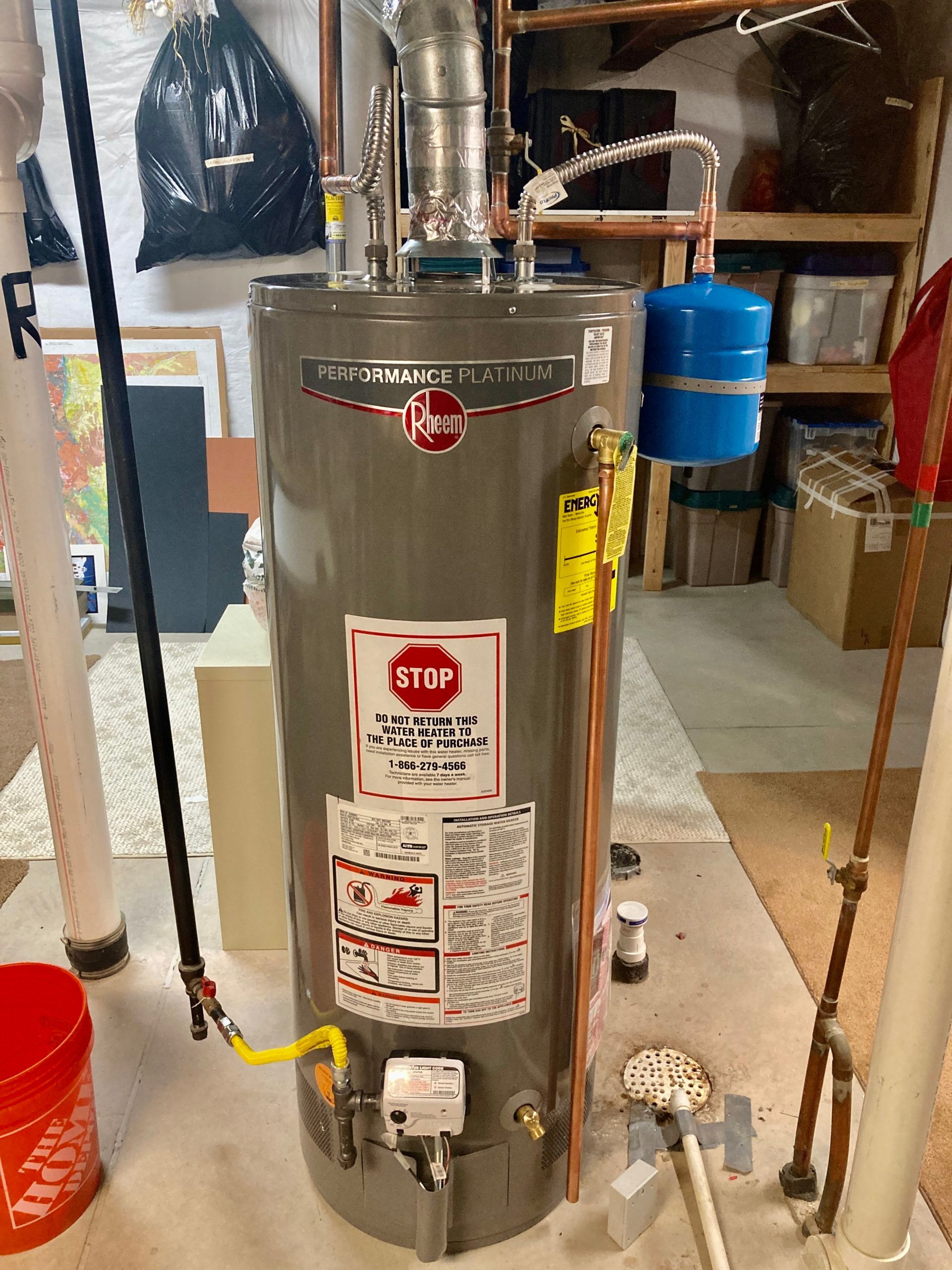 A water heater is sitting on the floor in a basement.