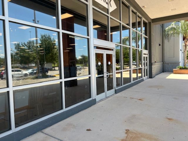 Modern storefront with large glass windows and central entrance, ideal for retail or commercial use, featuring ample space for signage. Front view