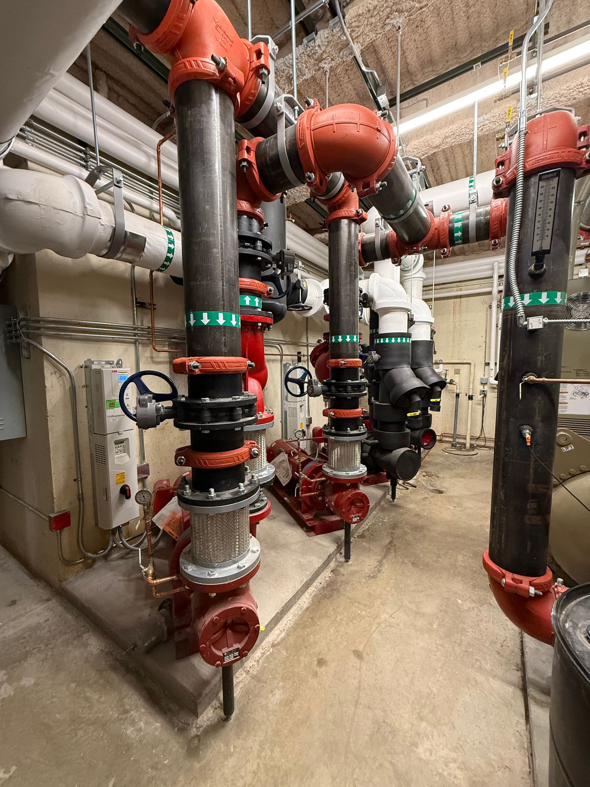 Red and black pipes with valves in an industrial setting.