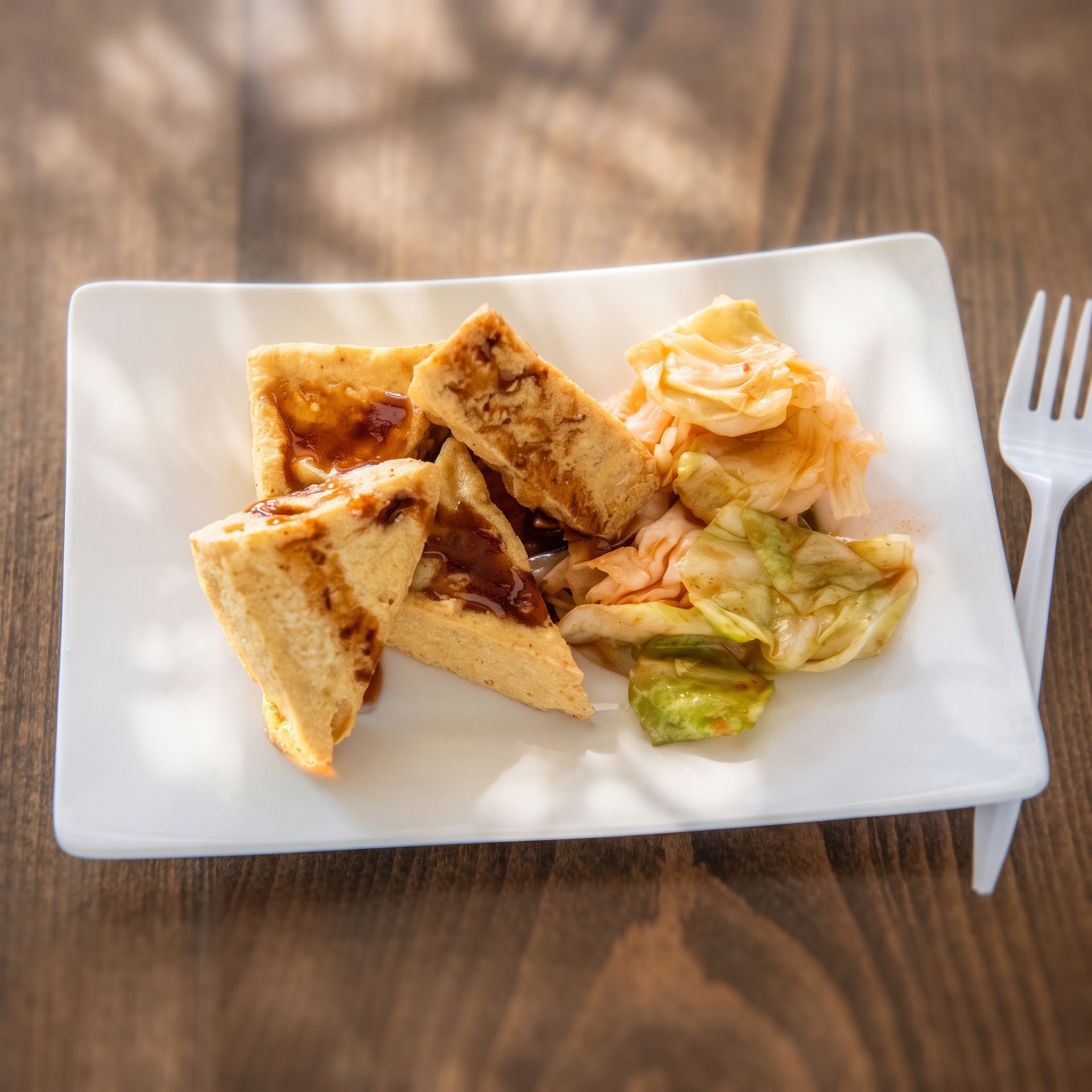 Grilled sandwich triangles on a white plate with salad, on a wooden table with a fork