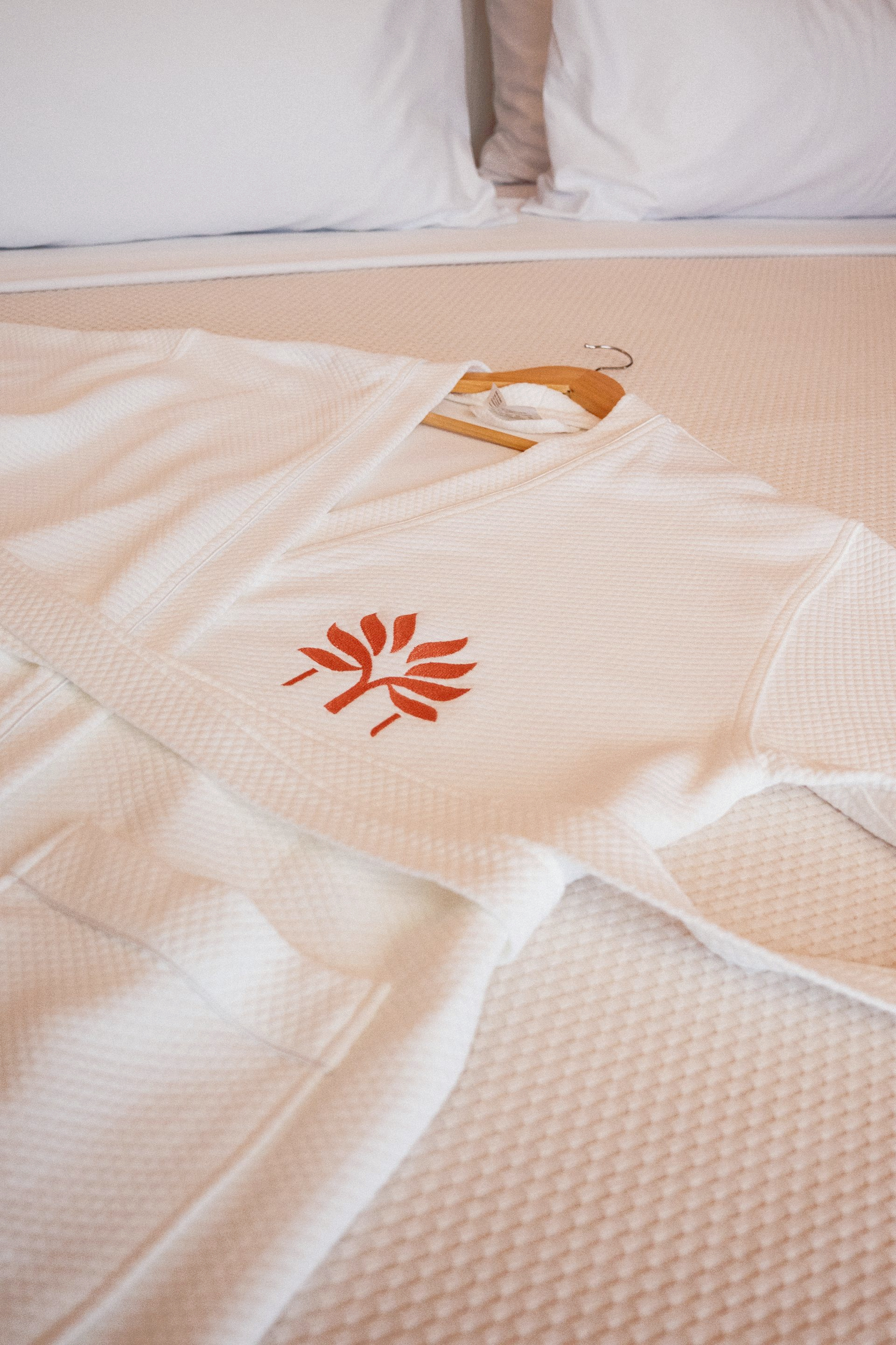 White robe placed on the bed with coral embroidery from the Zapadilly Hotel shop in San Andrés