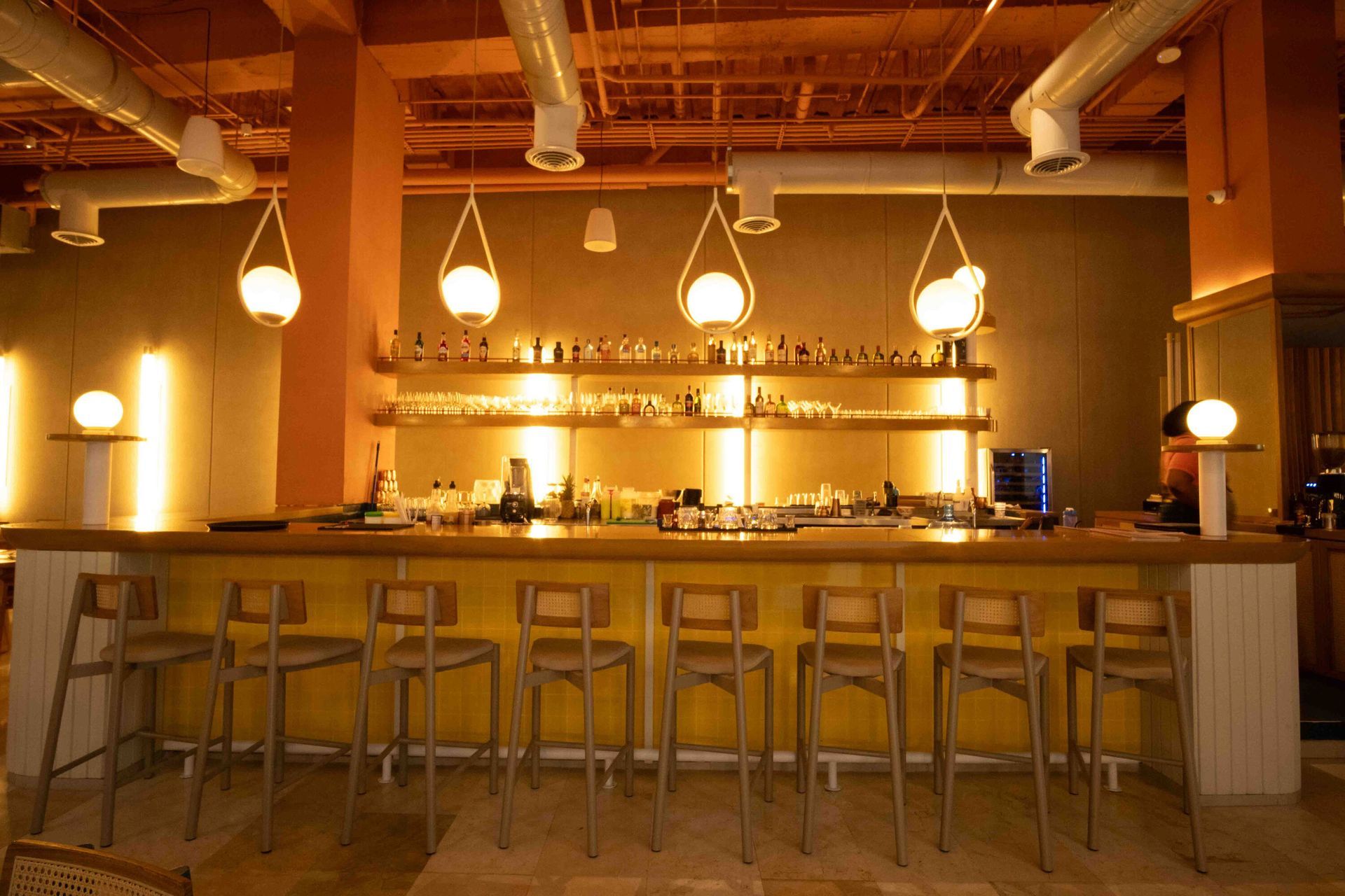 mejores restaurantes san andres, con mesa central de madera, sillas coral y azules, y cocina abierta.