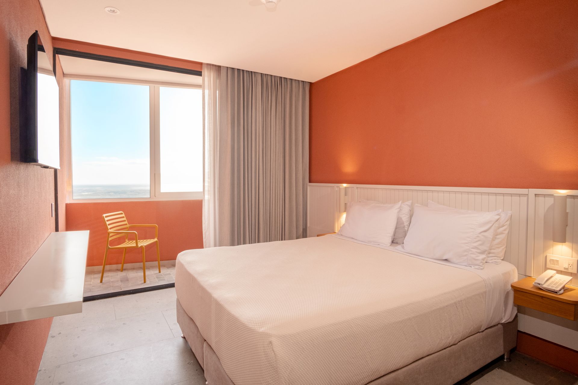 Habitaciones en San Andrés con cama queen, pared azul, lámpara de noche y balcón con vista exterior.