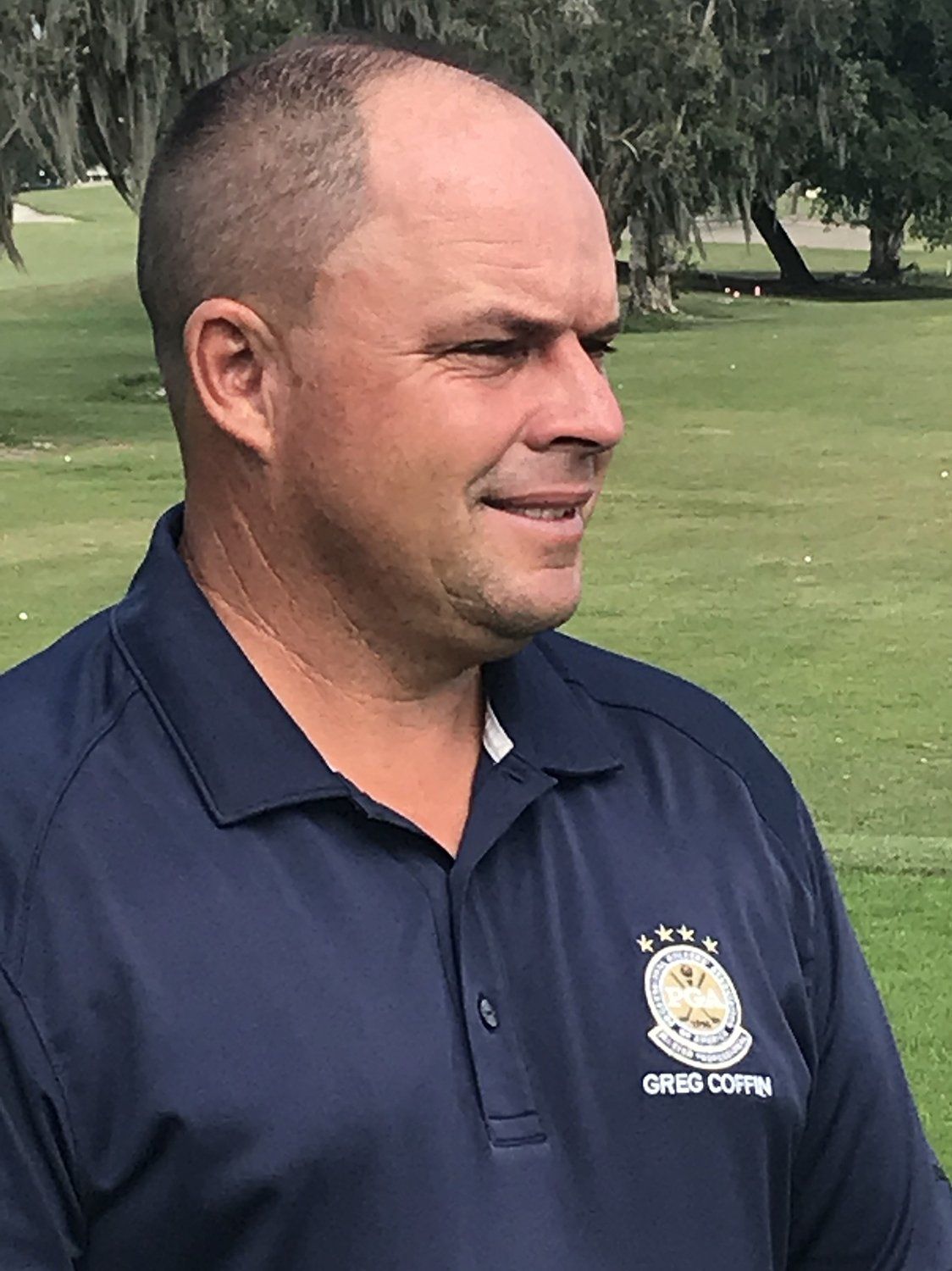 A man in a blue shirt is standing on a golf course.
