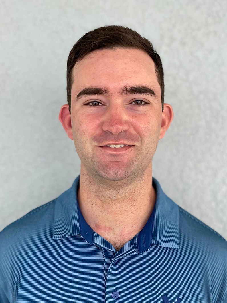 A man in a blue polo shirt is smiling for the camera.