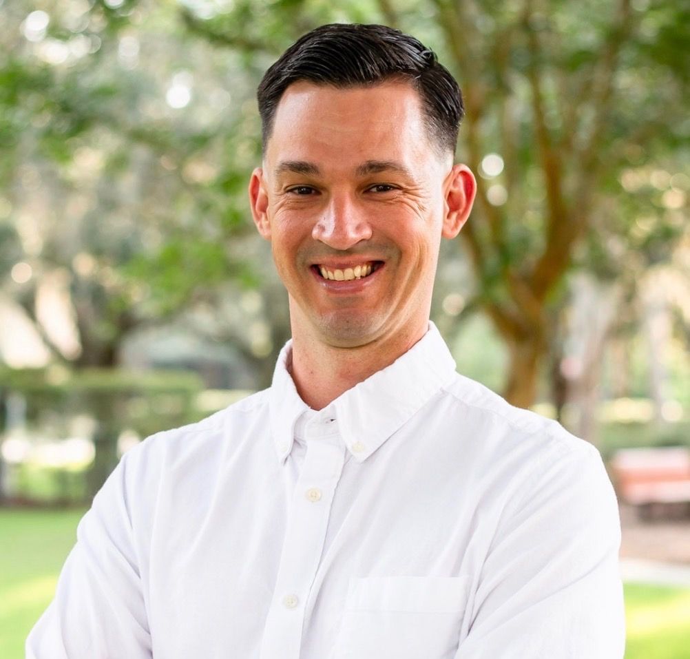 A man in a blue polo shirt is smiling for the camera.