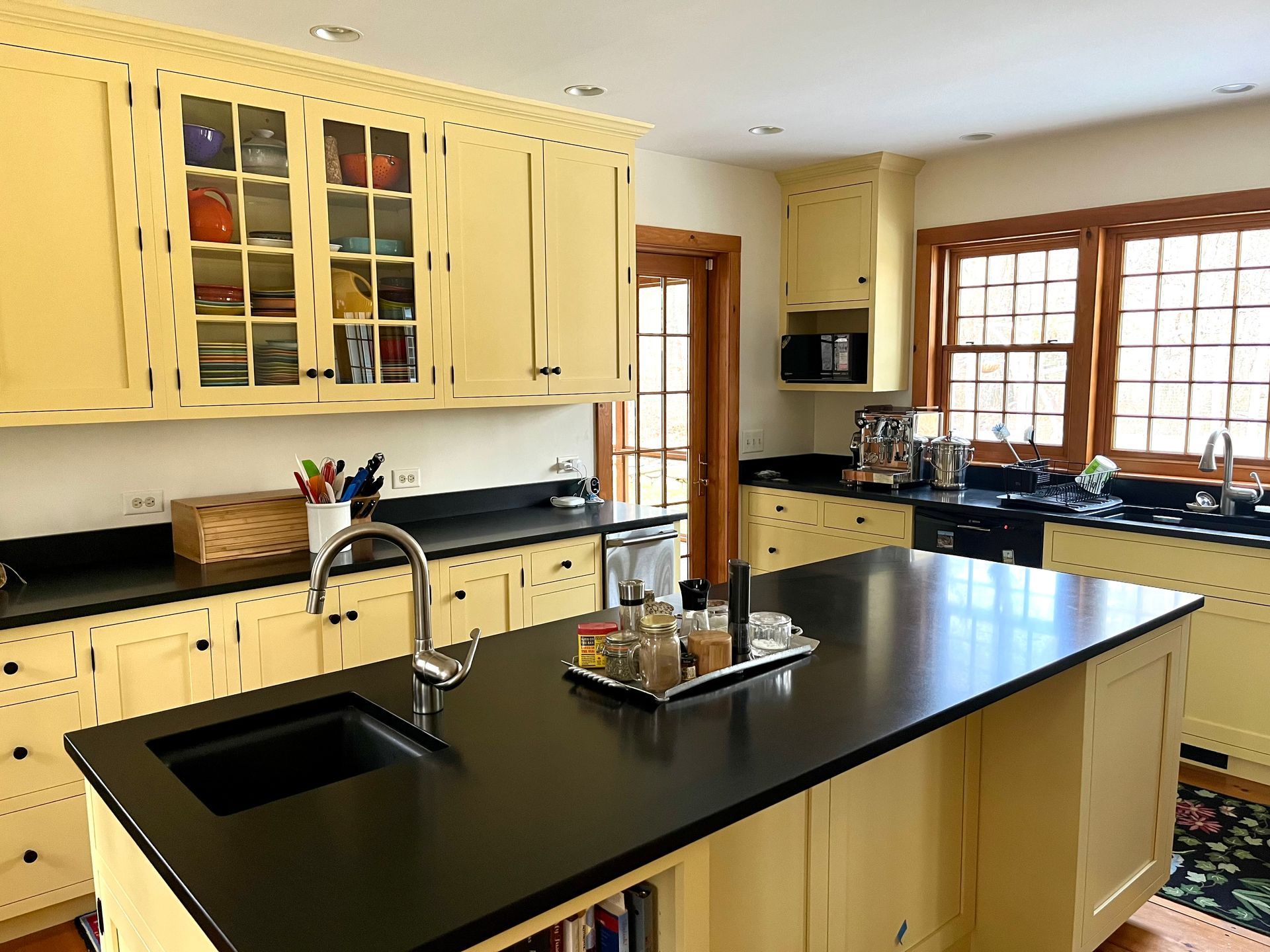 Bright kitchen with cream cabinets, black countertops, and a central island with a sink and faucet.