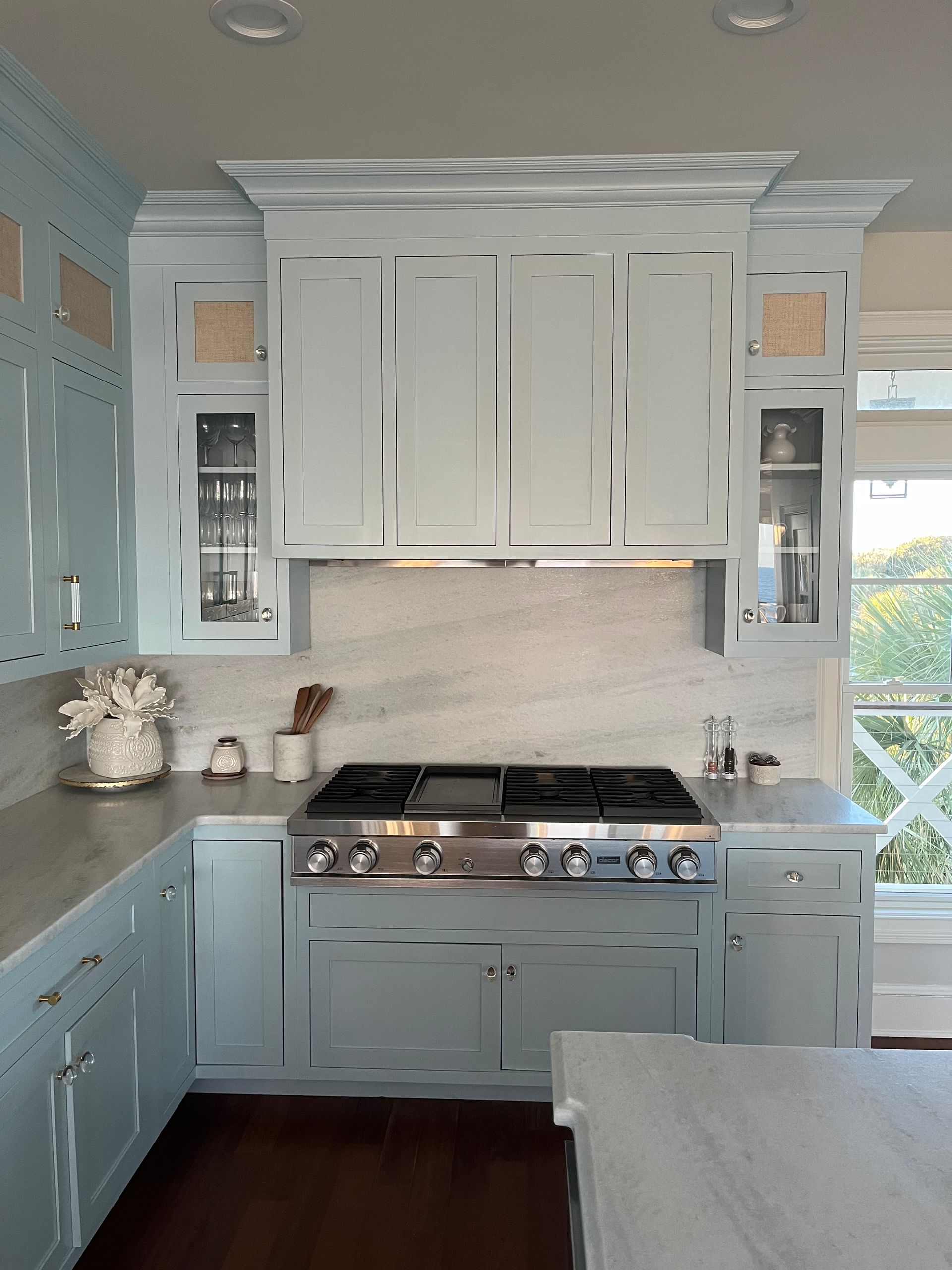 Bright white kitchen with built-in cabinets, stainless range, and marble countertops