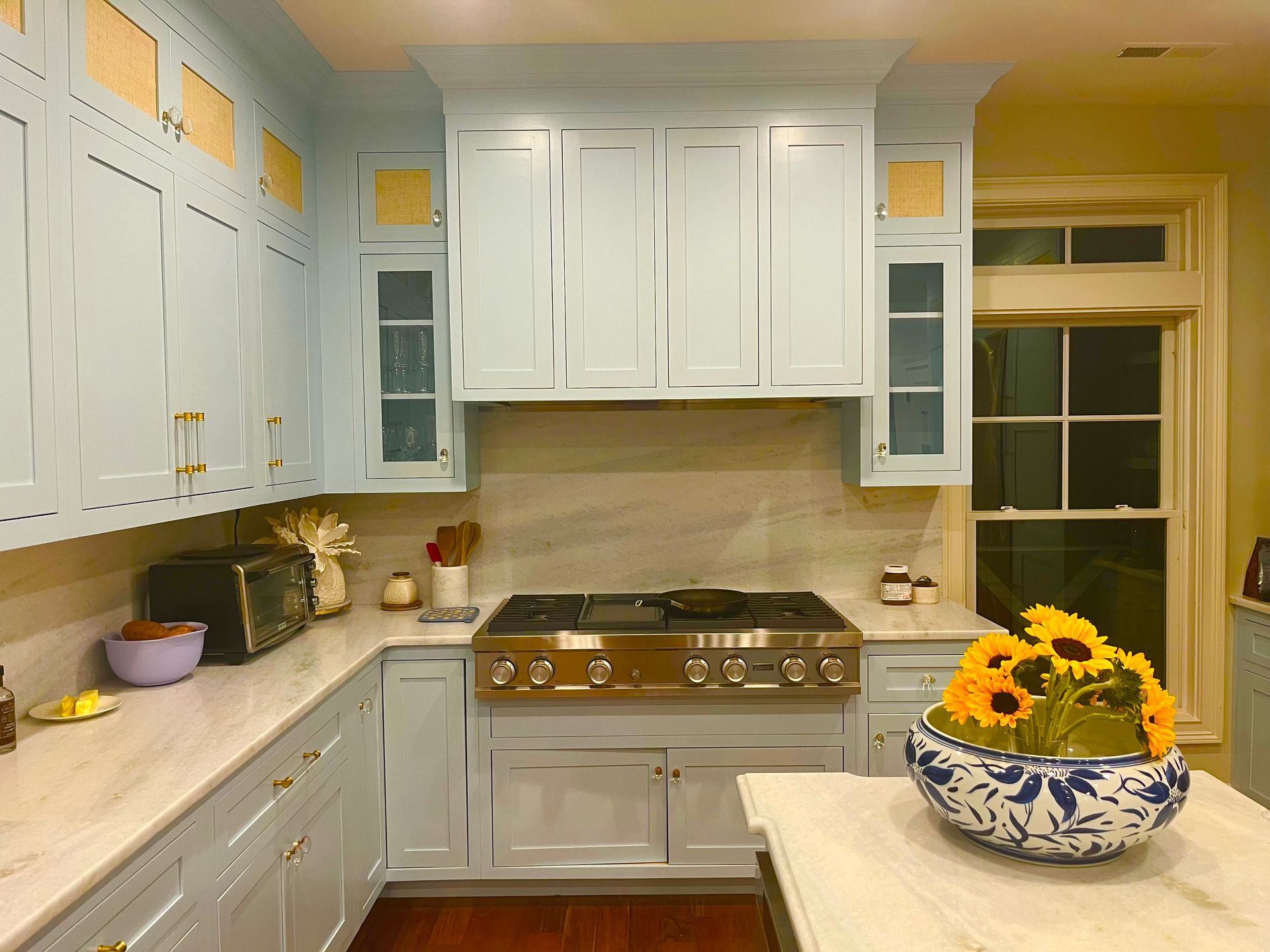 Bright white kitchen with blue accents, stainless stove, and a sunflower bowl on the island