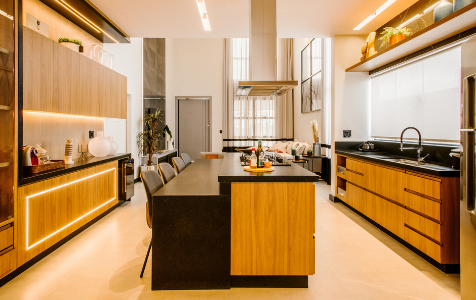 Modern kitchen interior with wood cabinets, black countertops, and a central island under warm lighting