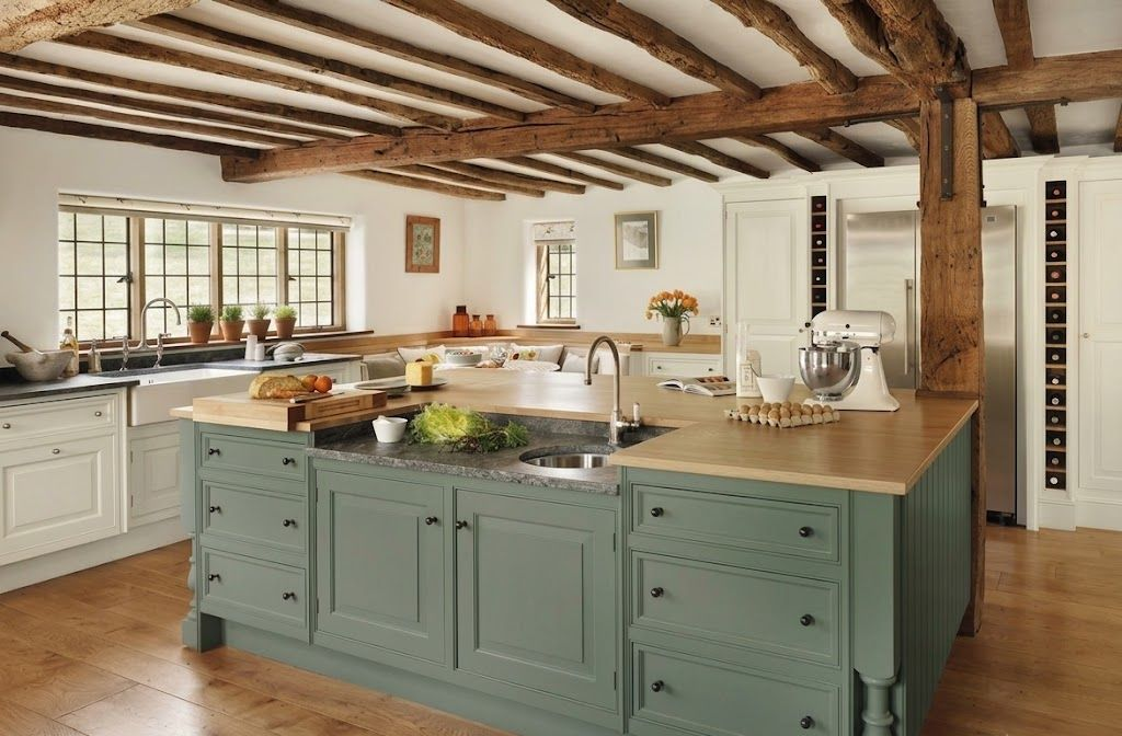 Rustic kitchen with sage island, wood beams, white cabinets, and bright natural light