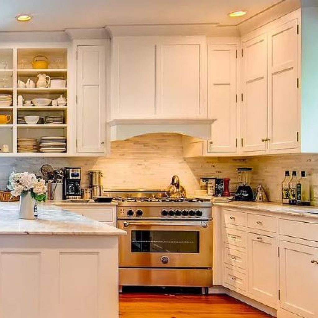 Bright white kitchen with stainless steel oven, marble island, open shelves, and cream tile backsplash