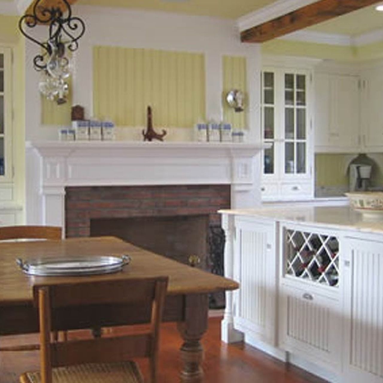Bright kitchen and dining area with white fireplace, wooden table, and built-in cabinets with wine rack.