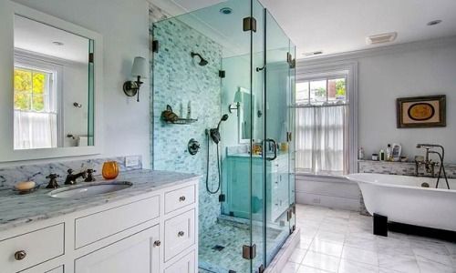 Bright bathroom with glass shower, white vanity, and freestanding tub by a window