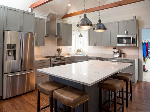 Modern kitchen with stainless appliances, gray cabinets, large island, and two pendant lights