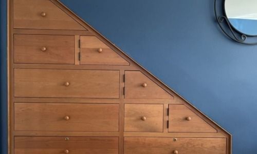 Wooden wall drawers arranged in a staircase pattern against a blue wall
