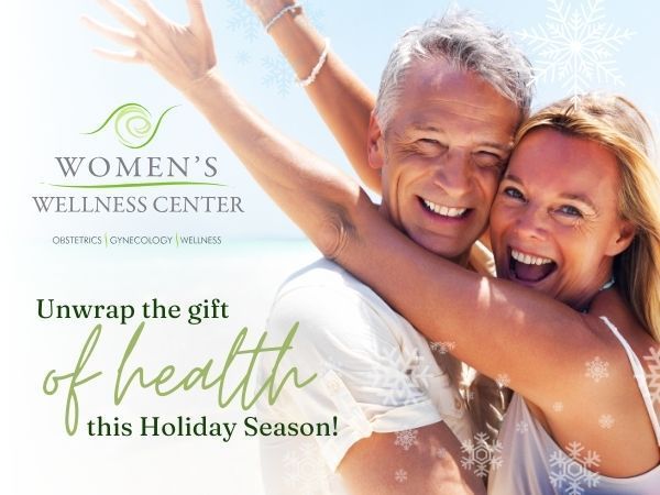 Smiling couple embracing, promoting Women's Wellness Center. Holiday message: