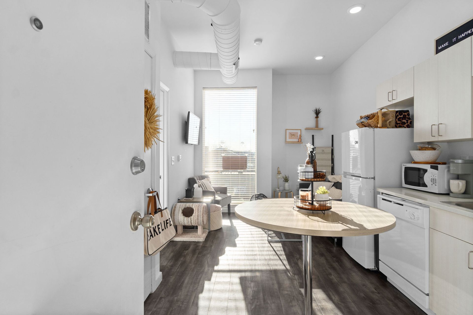 Photo showing a door opening to show the kitchen and living room of this apartment