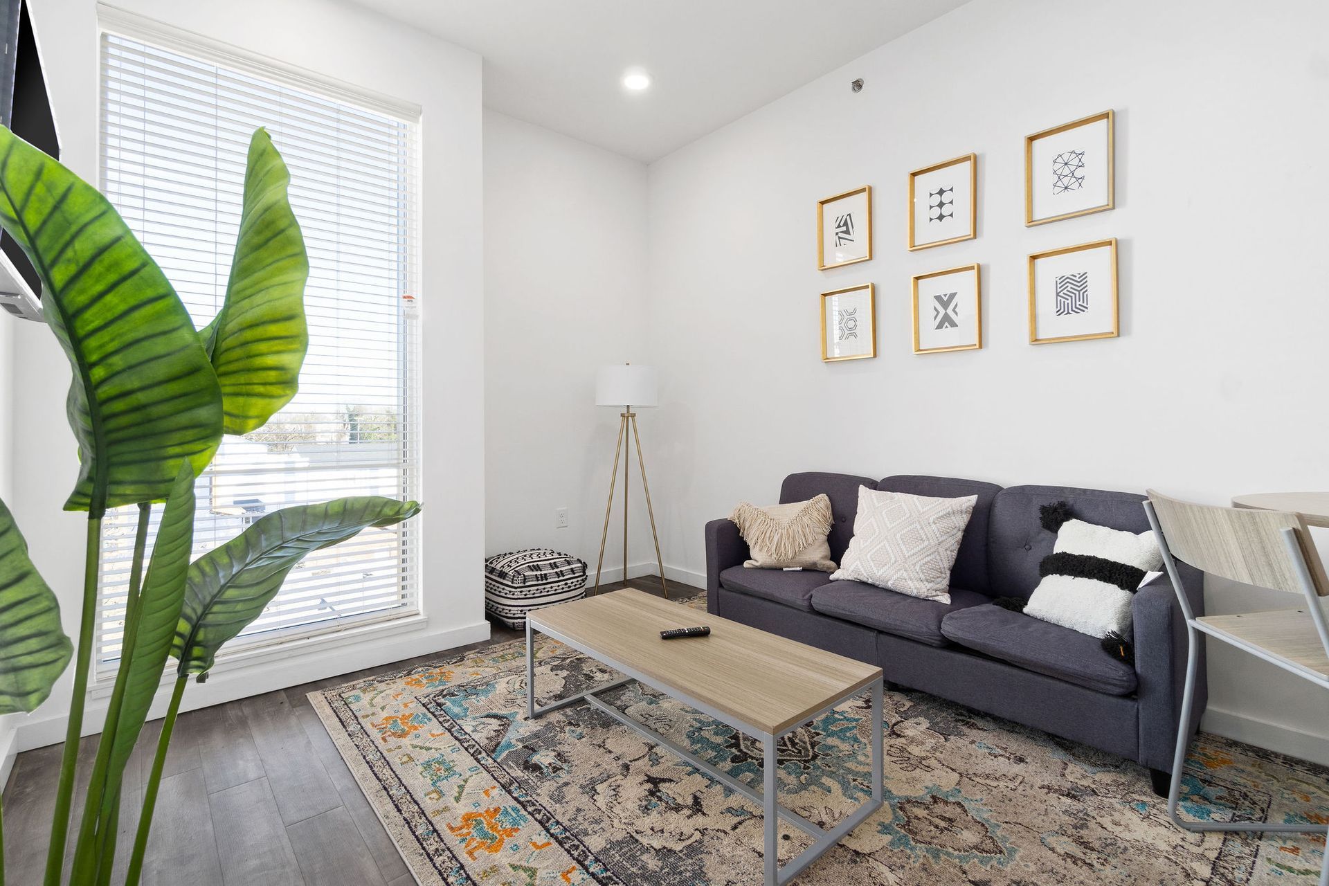 Clarksville, TN Student Apartments with In-Unit Washer and Dryer | Main608 | Living Room with Wood-Style Flooring, Area Rug, Sofa, Coffee Table, Ottoman Stool, Standing Lamp, and Large Window. 