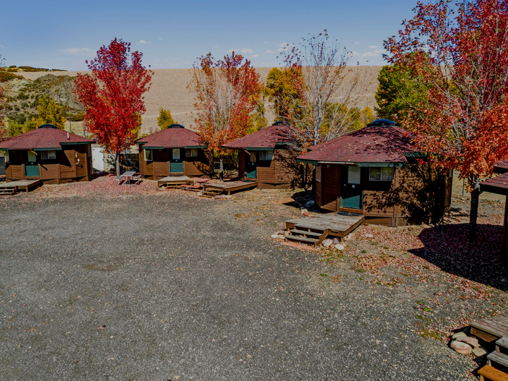 Wooden yurt accommodations at River's Edge RV Resort in Heber City, Utah, with fall mountain foliage in the background