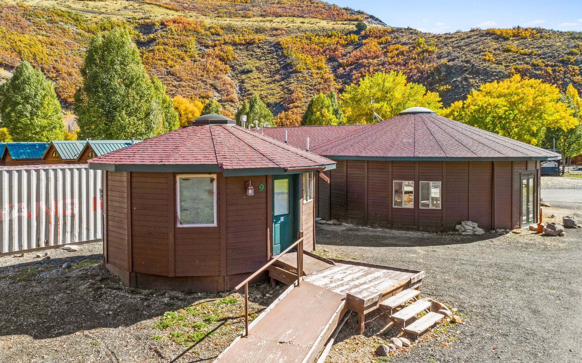 A small brown building with a red roof and a ramp in front of it.