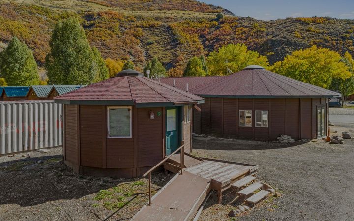 Wooden yurt accommodations at River's Edge RV Resort in Heber City, Utah, with fall mountain foliage in the background