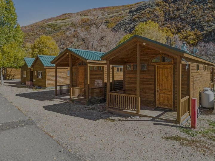 Row of park model cabins with covered porches and teal metal roofs at River's Edge RV Resort near Park City, Utah