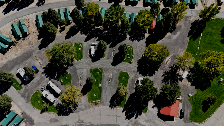 Full hookup RV sites at River's Edge RV Resort in Heber Valley, Utah, with large motorhomes parked among mature trees and mountain views