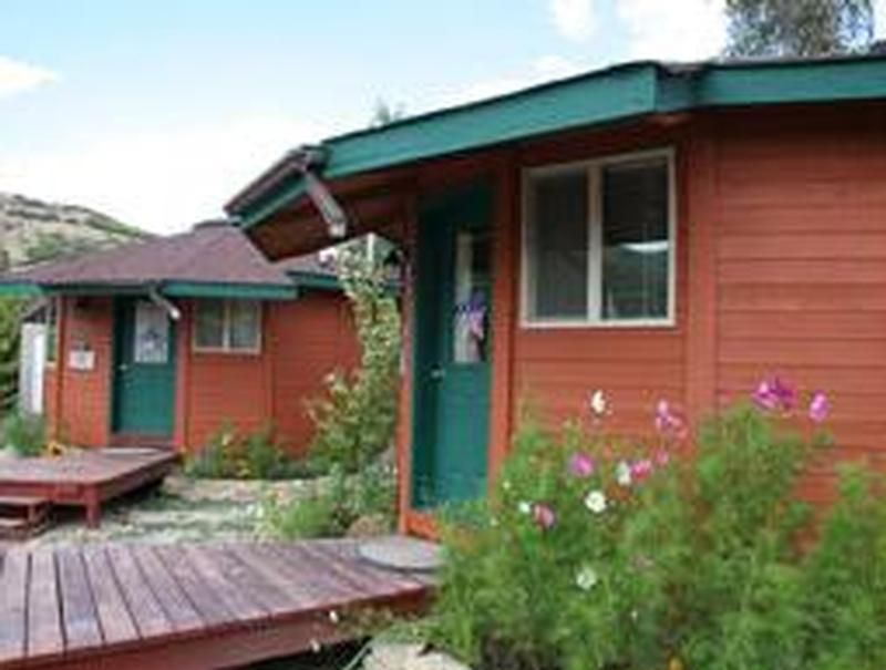 A wooden house with a green roof and a wooden deck in front of it.