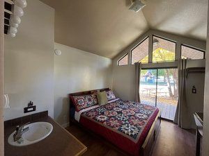 A bedroom with a bed , sink , and sliding glass doors.
