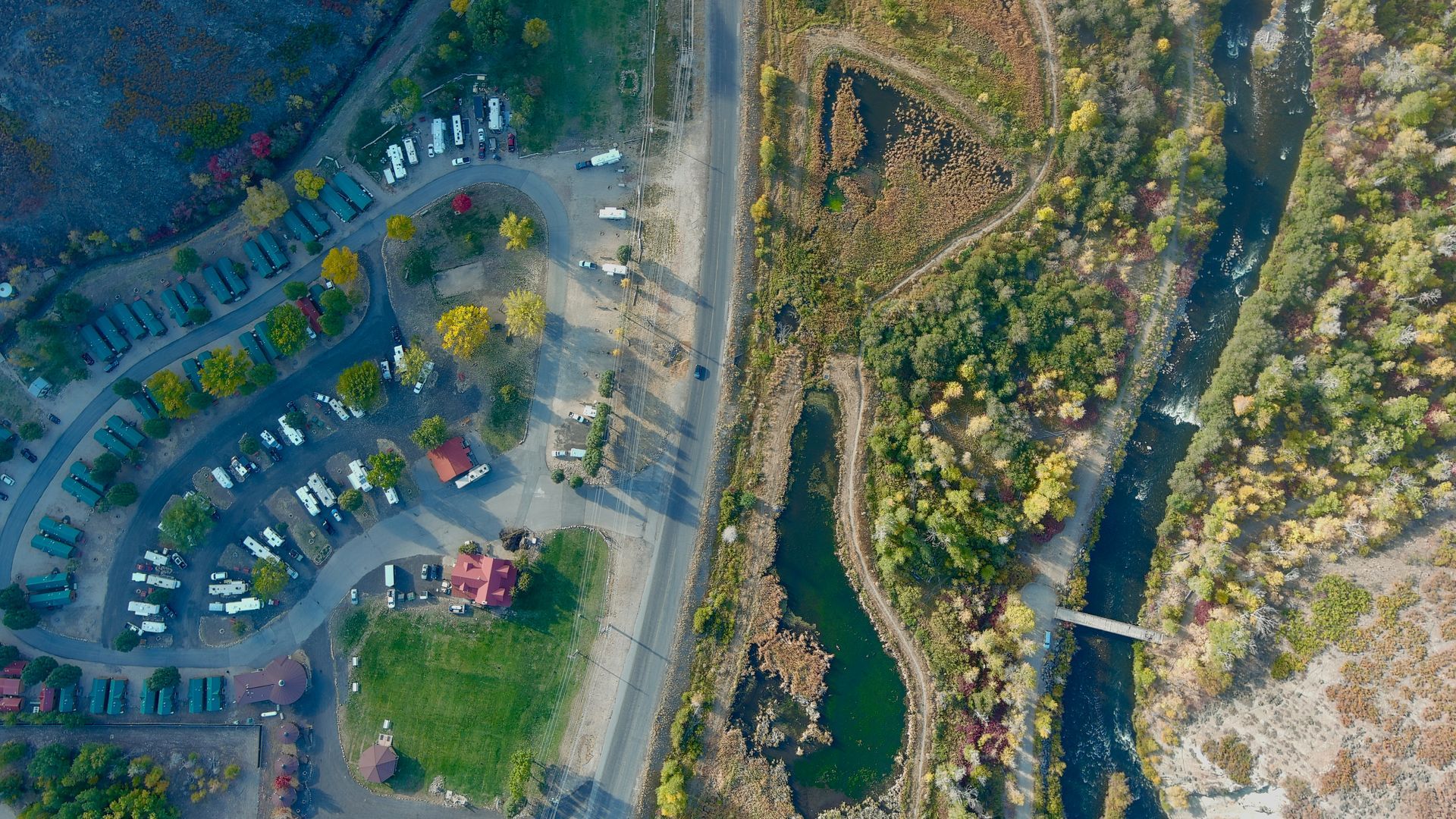 An aerial view of a park with a river and trees.